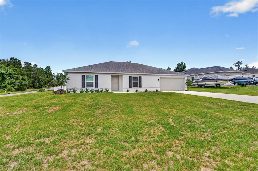A single-story house with a light-colored exterior, a two-car garage, and a large front lawn — 2686 SW 161ST LOOP, OCALA, FL