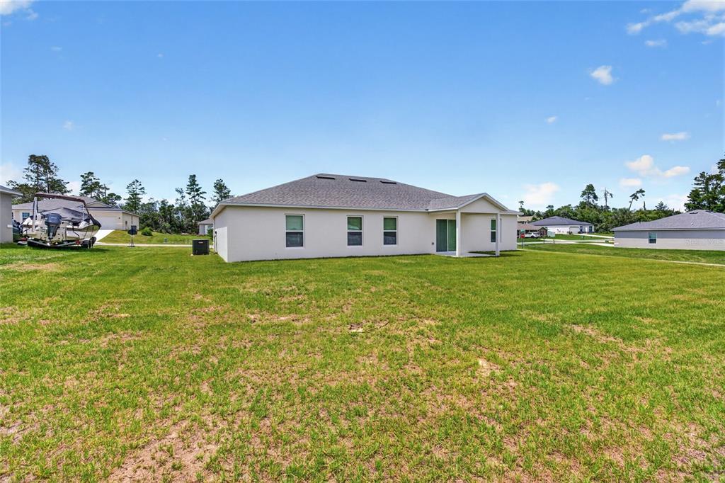 The exterior rear view of a single-story house features a large lawn and boat trailer — 2686 SW 161ST LOOP, OCALA, FL