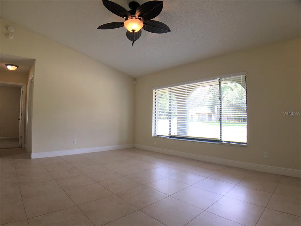 An empty room with light tile flooring, a ceiling fan, and a large window — 1927 E LAKE DRIVE, CASSELBERRY, FL
