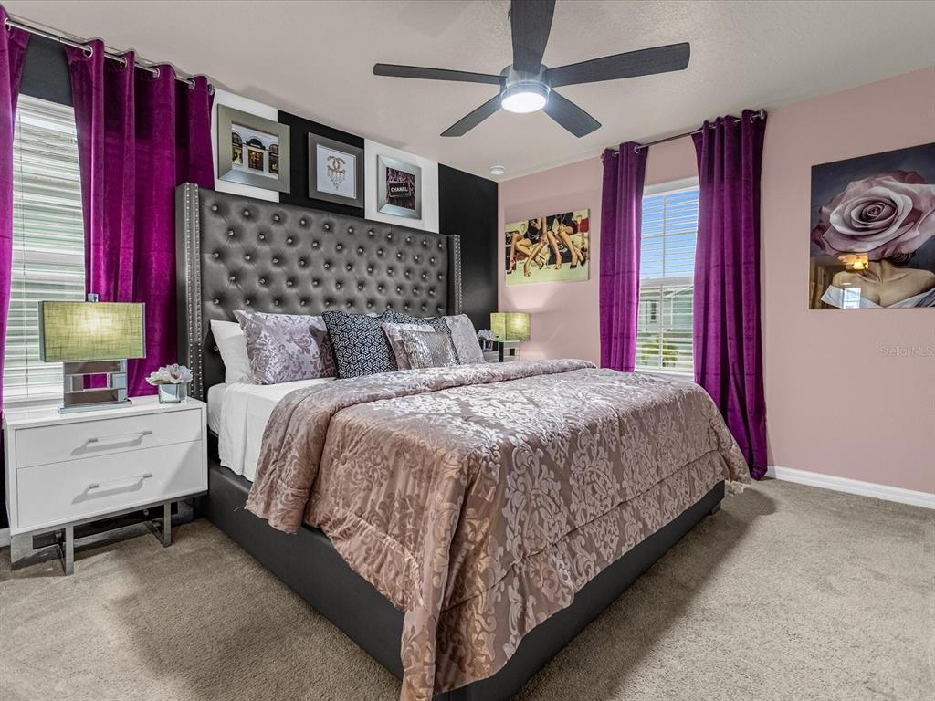 A bedroom features a tufted gray headboard, purple curtains, and a patterned bedspread — 1891 SUMMER DRIVE, DAVENPORT, FL