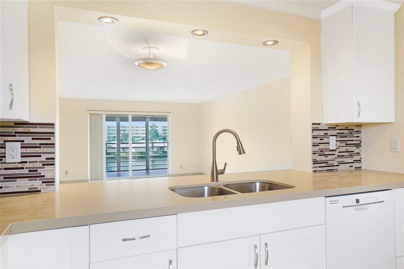 A kitchen with white cabinets, a stainless steel sink, and a view of a balcony — 111 SE 3rd Avenue # 306, Dania Beach FL 33004, DANIA BEACH, FL