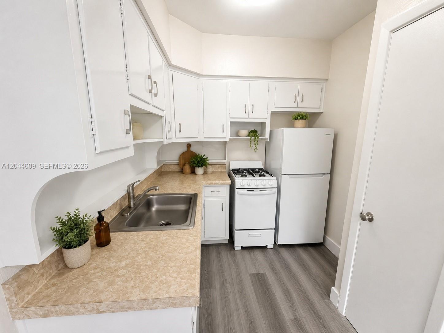 A kitchen features white cabinets, tan laminate countertops, a stainless steel sink, and white appliances — 34 Madeira Ave # 3, Coral Gables FL 33134, CORAL GABLES, FL