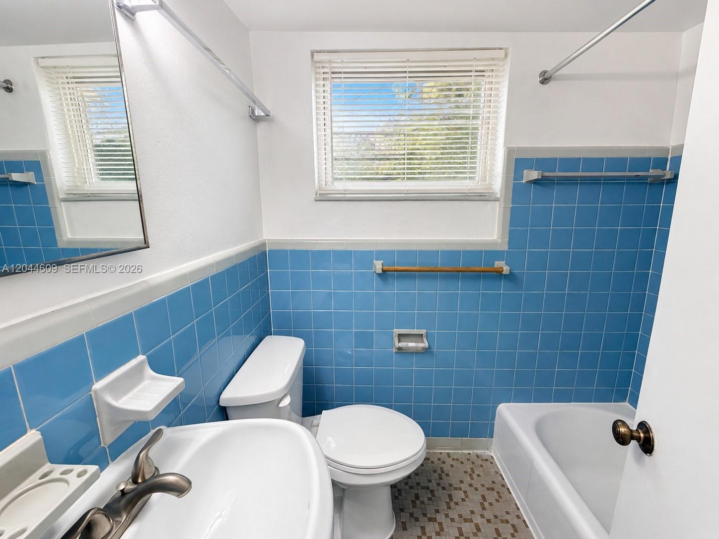 A bathroom features blue wall tiles, a white pedestal sink, a toilet, and a bathtub — 34 Madeira Ave # 3, Coral Gables FL 33134, CORAL GABLES, FL