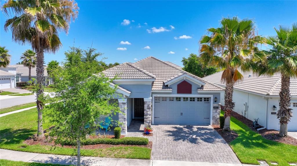 A single-story house with a gray exterior, a tiled roof, and a paved driveway — 1401 CLUBMAN DRIVE, DAVENPORT, FL