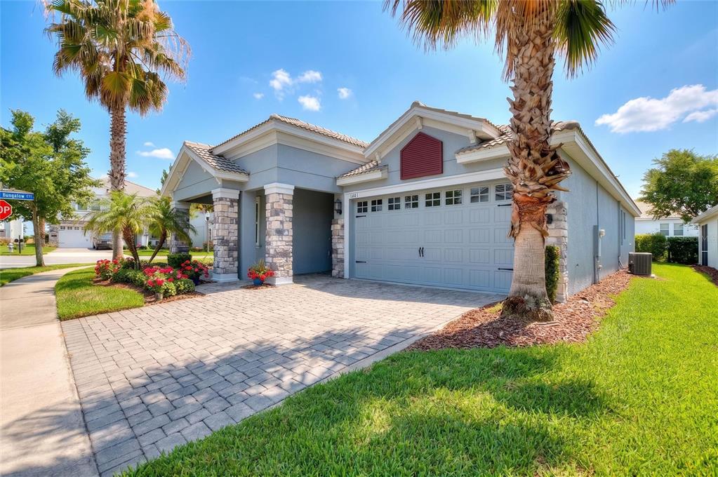 A single-story house with a paved driveway, stone accents, and palm trees in the front yard — 1401 CLUBMAN DRIVE, DAVENPORT, FL