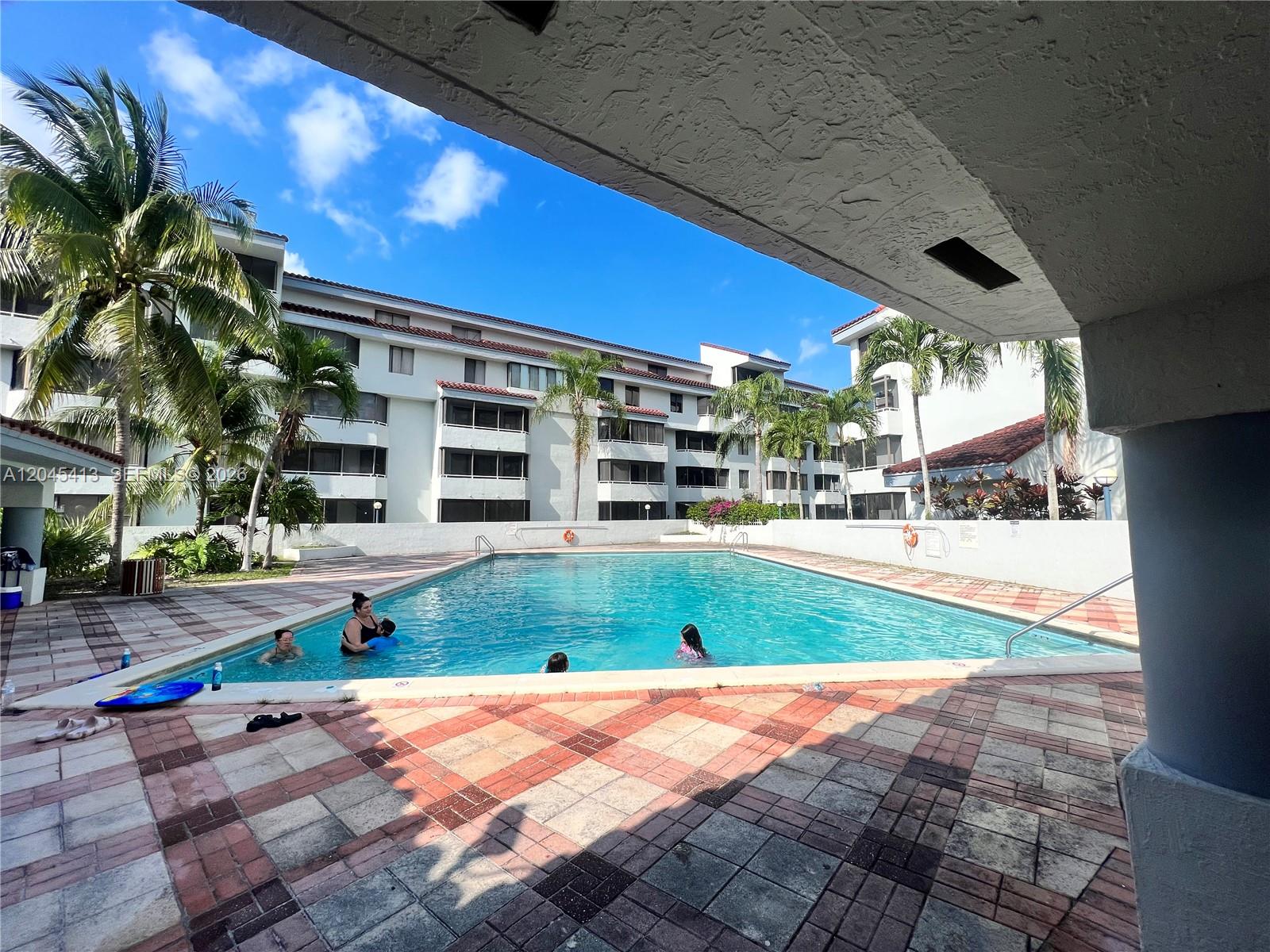 A swimming pool is surrounded by a tiled deck and multi-story apartment buildings — 8255 SW 152nd Ave # 209, Miami FL 33193, MIAMI, FL