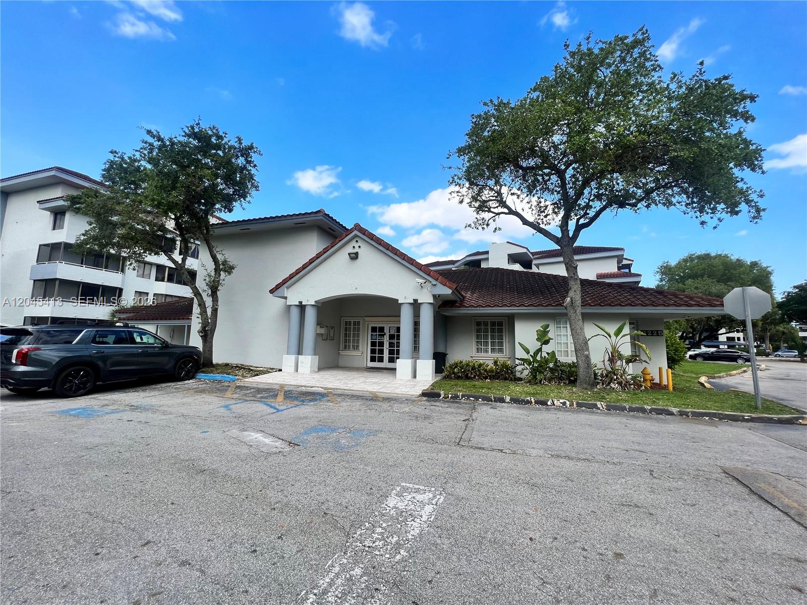 A single-story building with a tiled roof and a covered entrance stands in a parking lot — 8255 SW 152nd Ave # 209, Miami FL 33193, MIAMI, FL