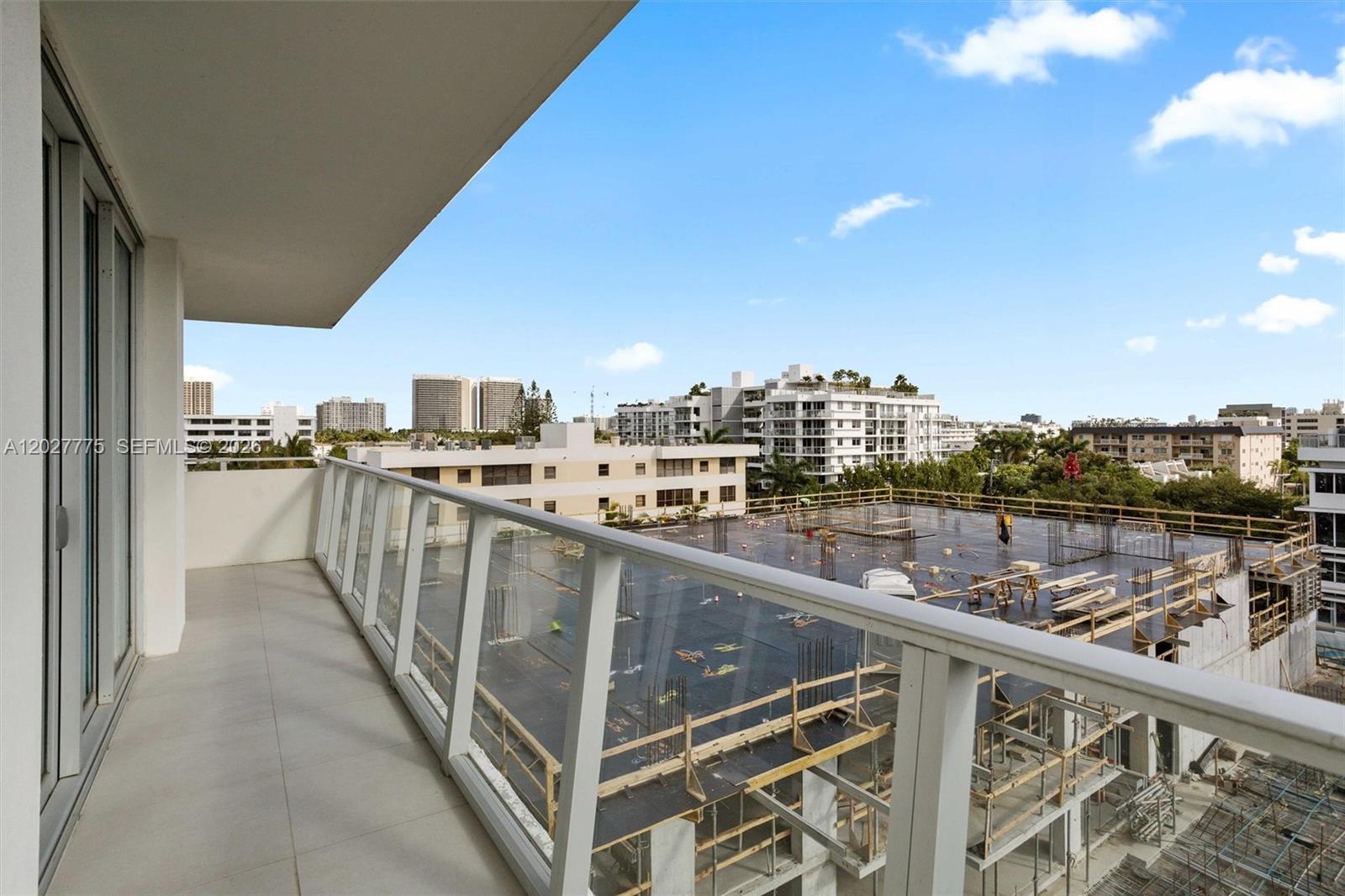 A balcony with a glass railing overlooks a construction site and surrounding city buildings — 1150 101st ST # 603, Bay Harbor Islands FL 33154, BAY HARBOR ISLANDS, FL