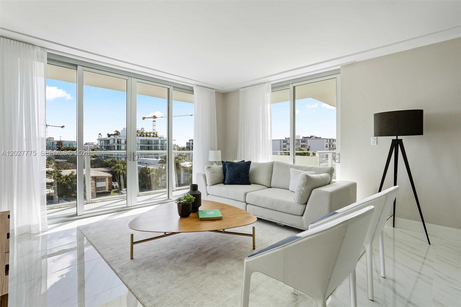 A bright living room features a white sofa, a triangular coffee table, and floor-to-ceiling windows — 1150 101st ST # 603, Bay Harbor Islands FL 33154, BAY HARBOR ISLANDS, FL