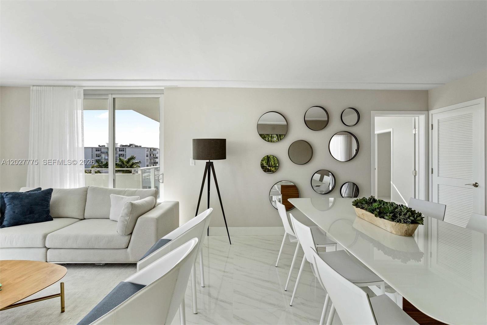 A bright living and dining area features white marble floors, a sofa, and wall mirrors — 1150 101st ST # 603, Bay Harbor Islands FL 33154, BAY HARBOR ISLANDS, FL