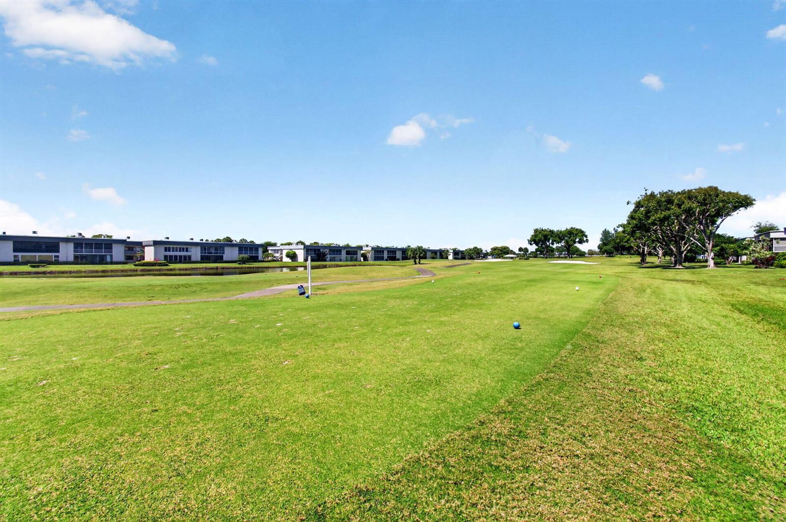 A view of a golf course fairway with apartment buildings in the background — 167 Normandy # D, Delray Beach FL 33484, DELRAY BEACH, FL