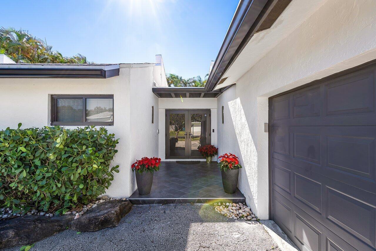 A white house exterior features a dark gray garage door and a recessed front entryway — 630 NE 15th Place, Boynton Beach FL 33435, BOYNTON BEACH, FL