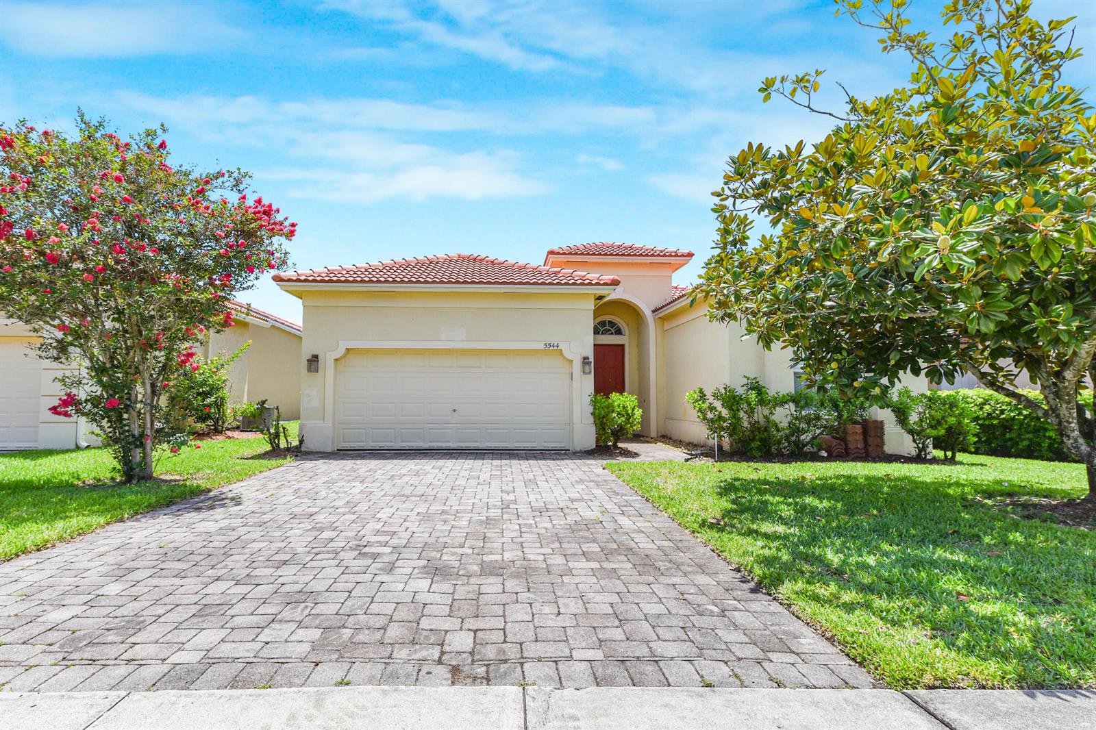 A single-story house with a paved driveway, a two-car garage, and a red front door — 5544 Spanish River Road, Fort Pierce FL 34951, FORT PIERCE, FL