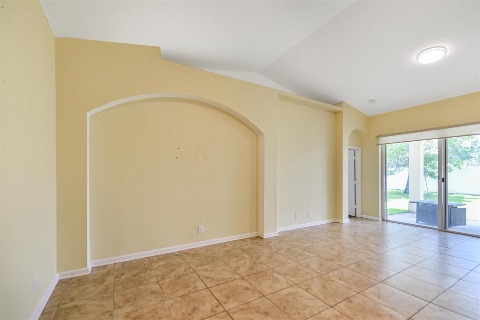 A living room features beige walls, a large arched wall niche, and tiled flooring — 5544 Spanish River Road, Fort Pierce FL 34951, FORT PIERCE, FL