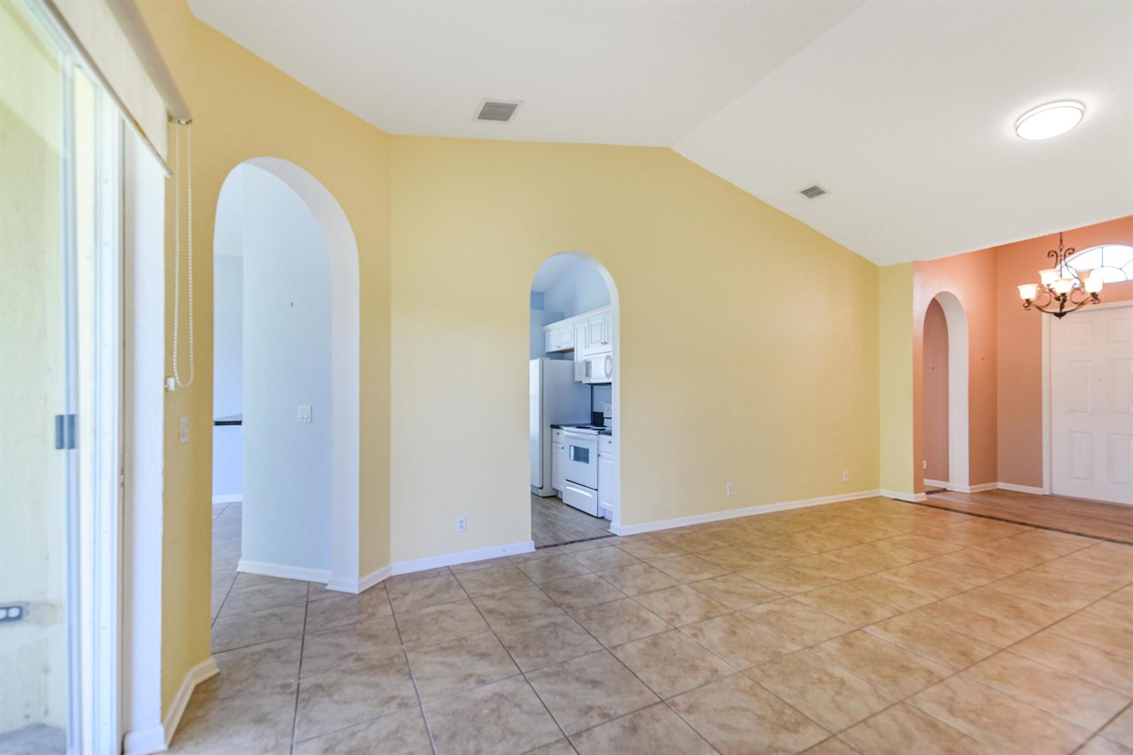A living area with tile floors, yellow walls, vaulted ceilings, and multiple arched doorways — 5544 Spanish River Road, Fort Pierce FL 34951, FORT PIERCE, FL