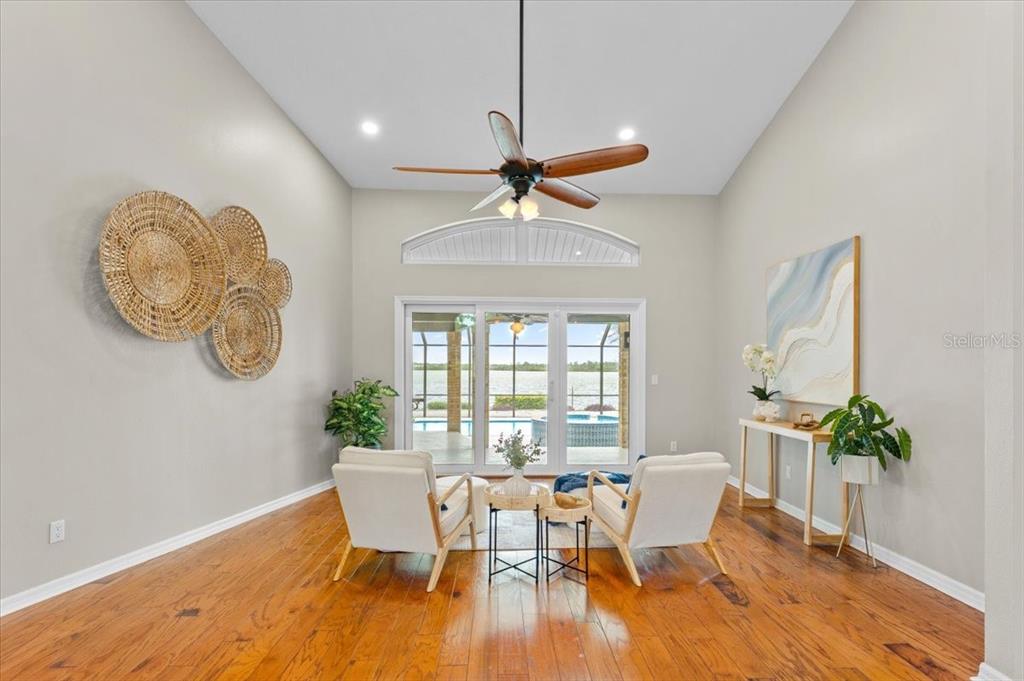 A sunlit living area features hardwood floors, two white chairs, and a view of water — 1589 MARY LANE, TARPON SPRINGS, FL