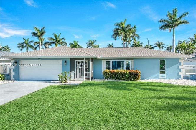 A light blue single-story house features a white garage door and palm trees outside — 355 Bayshore Dr, Cape Coral FL 33904, CAPE CORAL, FL