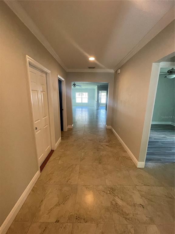 A hallway with beige tile flooring leads toward a bright, open living area — 232 CLAYTON STREET, BRANDON, FL