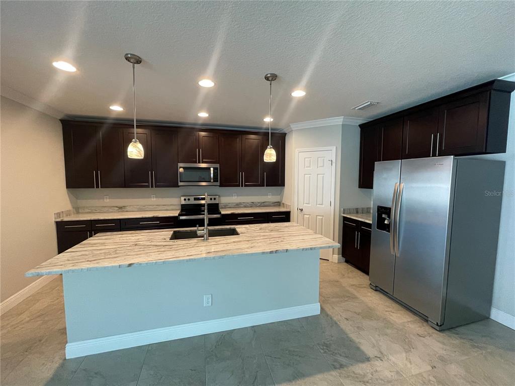 A kitchen features dark wood cabinets, stainless steel appliances, and a large stone-topped island — 232 CLAYTON STREET, BRANDON, FL