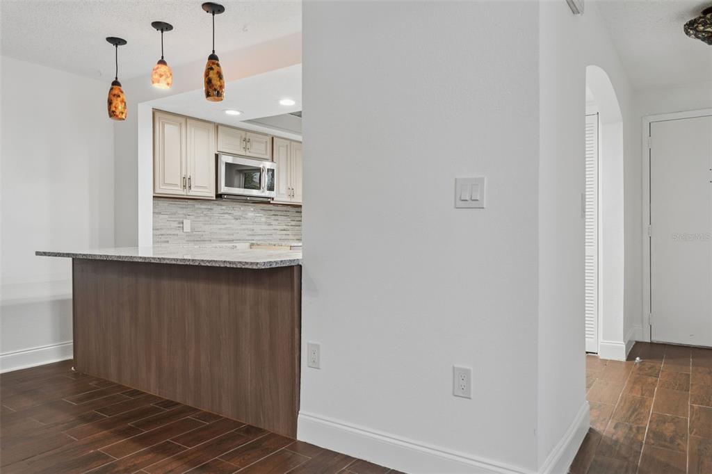 A kitchen with a granite breakfast bar, pendant lighting, and wood-look tile flooring — 9920 EAGLES POINT CIRCLE UNIT 2, PORT RICHEY, FL