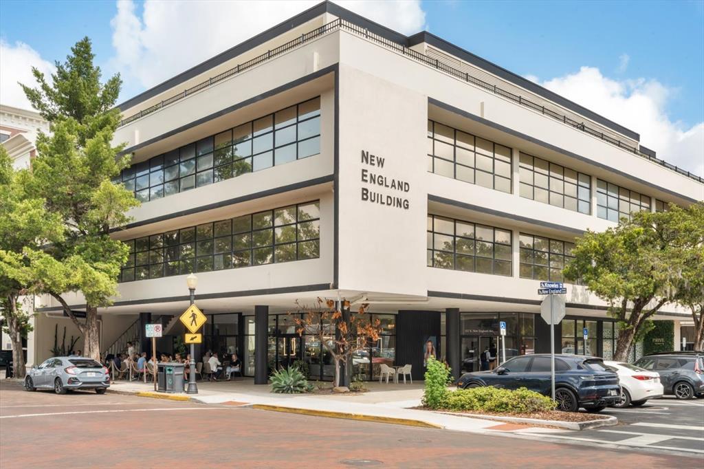 A three-story commercial building with large windows and a ground-floor restaurant on a corner lot — 157 E NEW ENGLAND AVENUE UNIT 302, WINTER PARK, FL