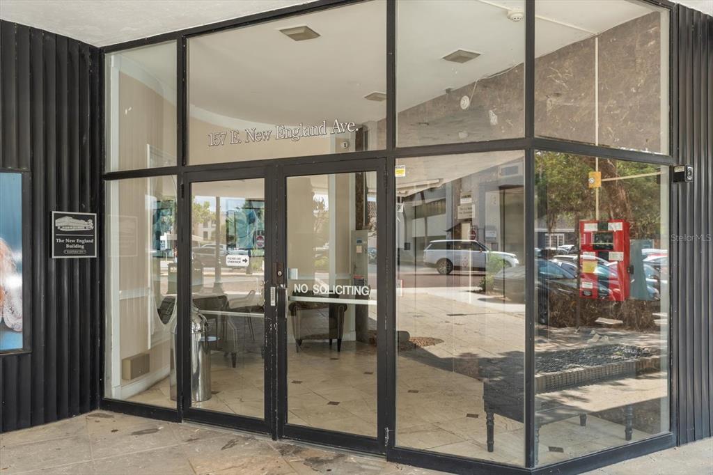 The glass-paned entrance of a commercial building features a black frame and double doors — 157 E NEW ENGLAND AVENUE UNIT 302, WINTER PARK, FL
