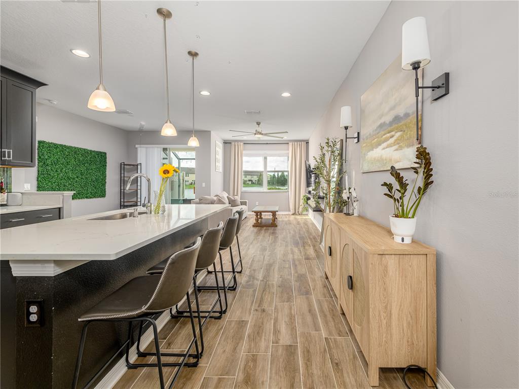 A kitchen island with bar seating overlooks a living area with wood-look tile flooring — 29844 SOUTHWELL LANE, WESLEY CHAPEL, FL