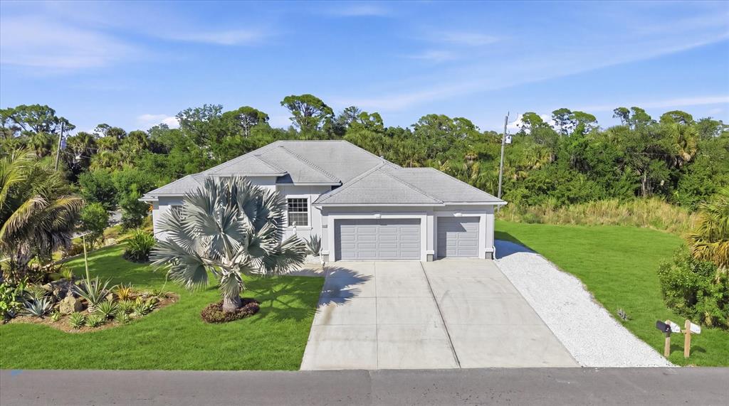 A single-story house with a gray roof, two garage doors, and a landscaped front yard — 1112 SENECA ROAD, VENICE, FL