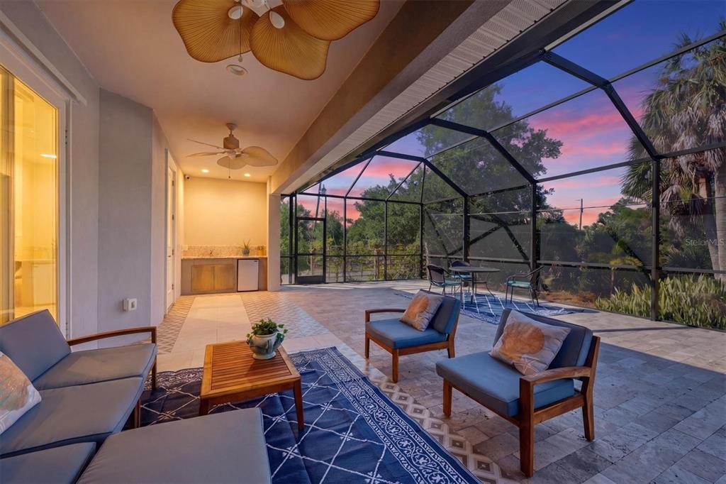 A covered outdoor patio features a screened enclosure, lounge furniture, and a small kitchenette area — 1112 SENECA ROAD, VENICE, FL