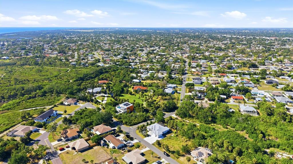 An aerial view shows a suburban neighborhood with houses, roads, and surrounding green vegetation — 1112 SENECA ROAD, VENICE, FL