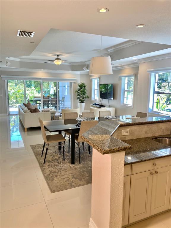 An open-concept kitchen and dining area features tile flooring, granite countertops, and sliding glass doors — 7652 WHISPER WAY UNIT 104, REUNION, FL