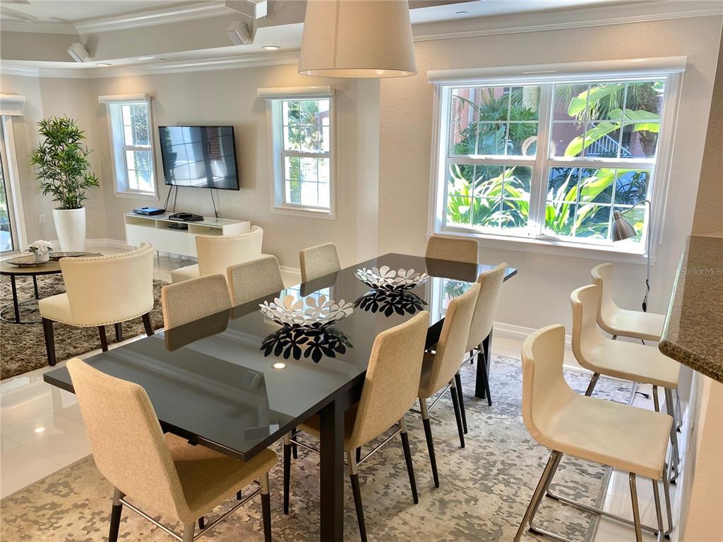 A dining room with a glass-topped table, beige chairs, and a large window — 7652 WHISPER WAY UNIT 104, REUNION, FL