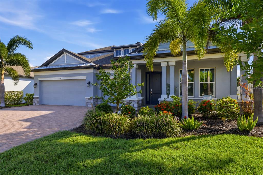 A single-story house with a gray exterior, a two-car garage, and a landscaped front yard — 5542 NATIVE HENNA COURT, SARASOTA, FL