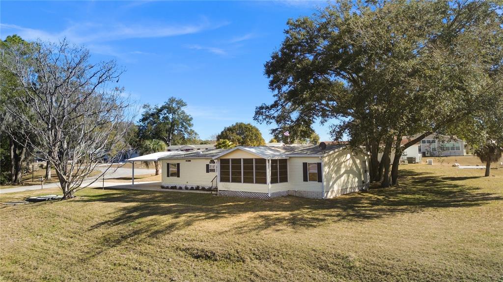 A light yellow manufactured home with a screened-in porch sits on a grassy lot — 7964 SW 6TH PLACE, OCALA, FL