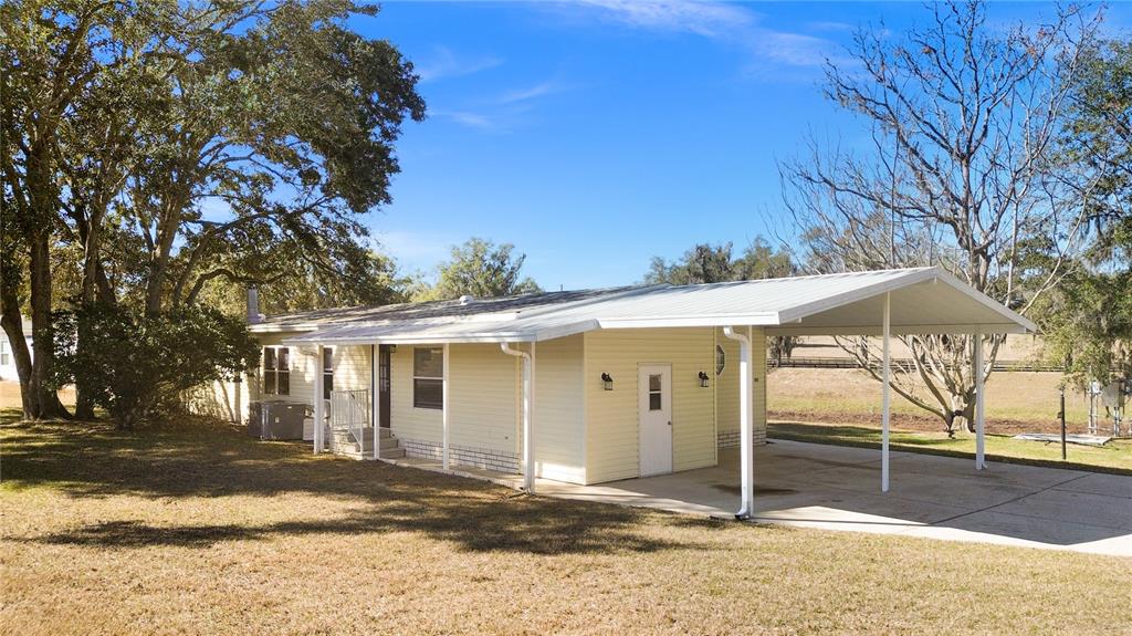 A light yellow single-story house with a metal roof and an attached carport — 7964 SW 6TH PLACE, OCALA, FL