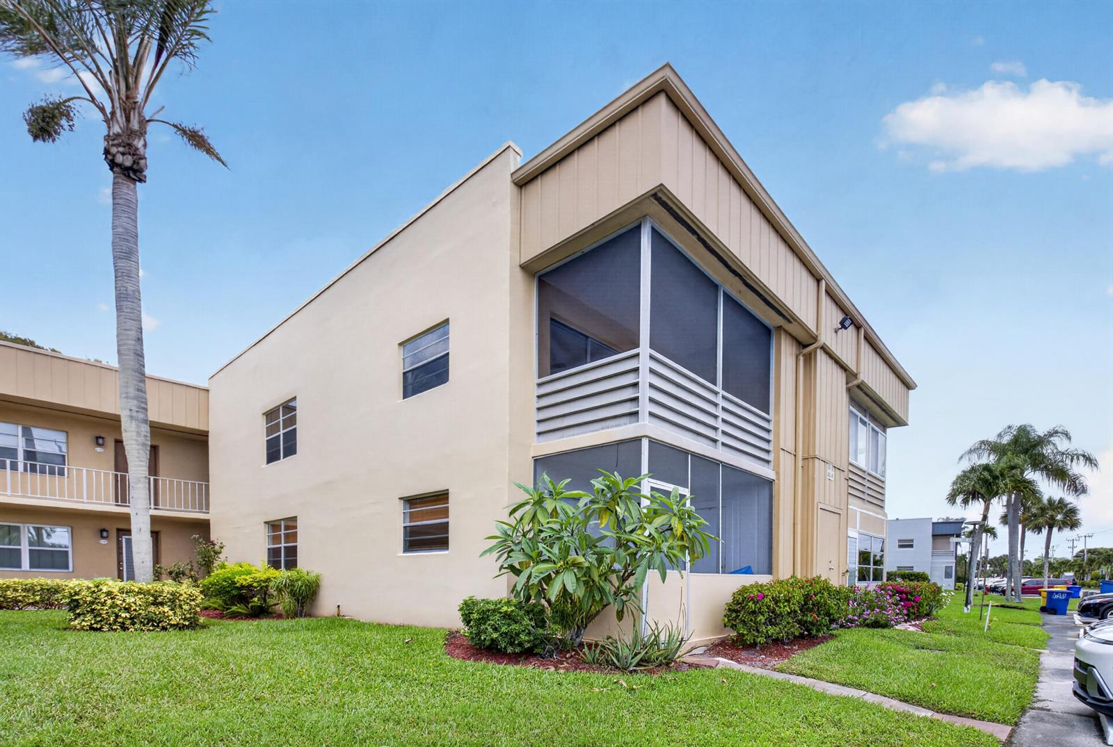 A two-story apartment building with tan stucco walls and screened-in balconies on the corner — 506 E Capri Road # 506, Delray Beach FL 33484, DELRAY BEACH, FL