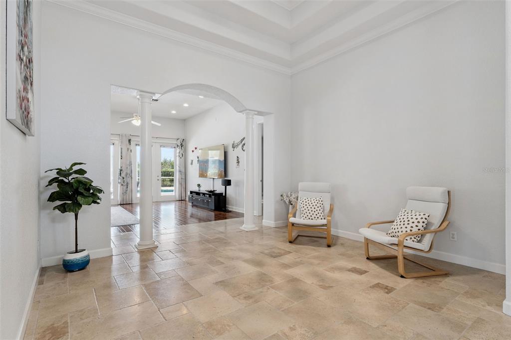 A bright, open-concept living area features tile flooring, white walls, and two modern armchairs — 1700 LAKE ROBERTS COURT, WINDERMERE, FL