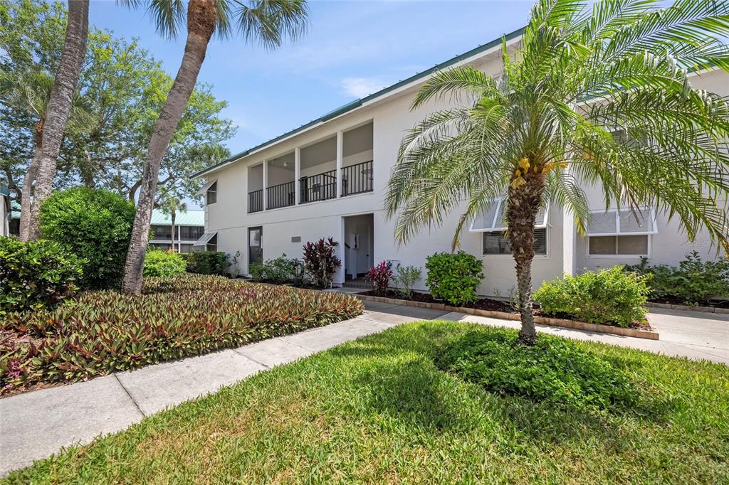 A two-story residential building with a screened balcony, palm trees, and landscaped front yard — 5619 MIDNIGHT PASS ROAD UNIT 503, SARASOTA, FL