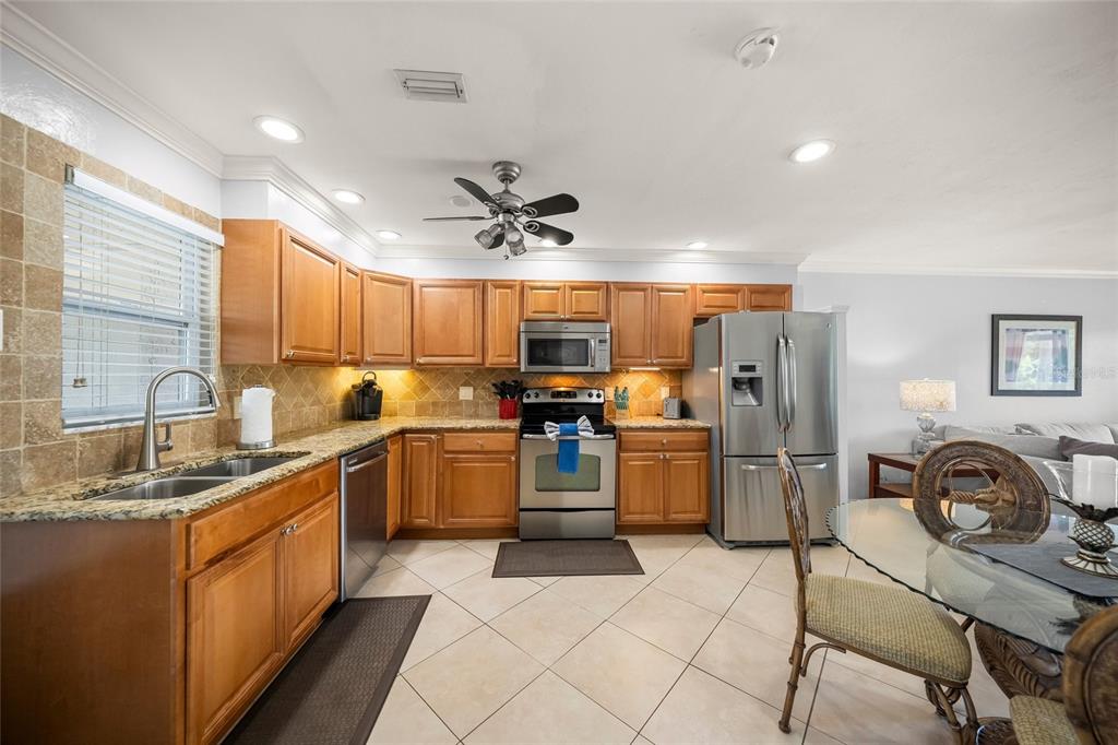 A kitchen with wood cabinets, stainless steel appliances, granite countertops, and tile flooring — 5619 MIDNIGHT PASS ROAD UNIT 503, SARASOTA, FL