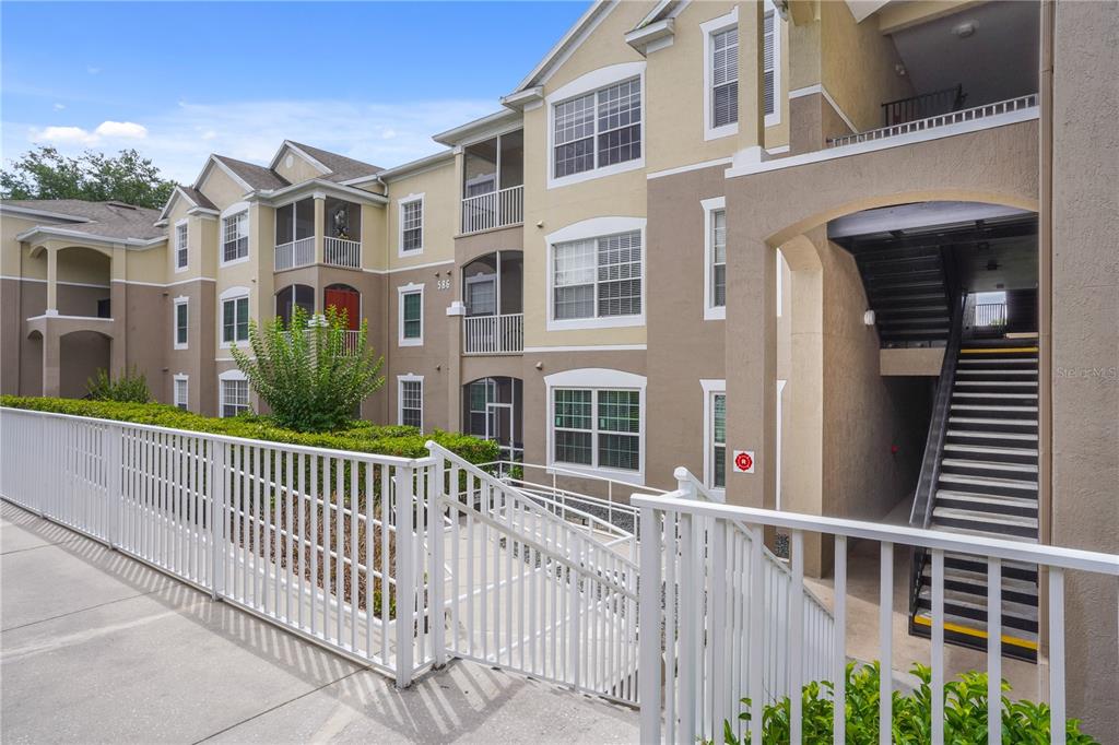 An exterior view of a multi-story apartment building with stairs and a white metal railing — 586 BRANTLEY TERRACE WAY UNIT 306, ALTAMONTE SPRINGS, FL