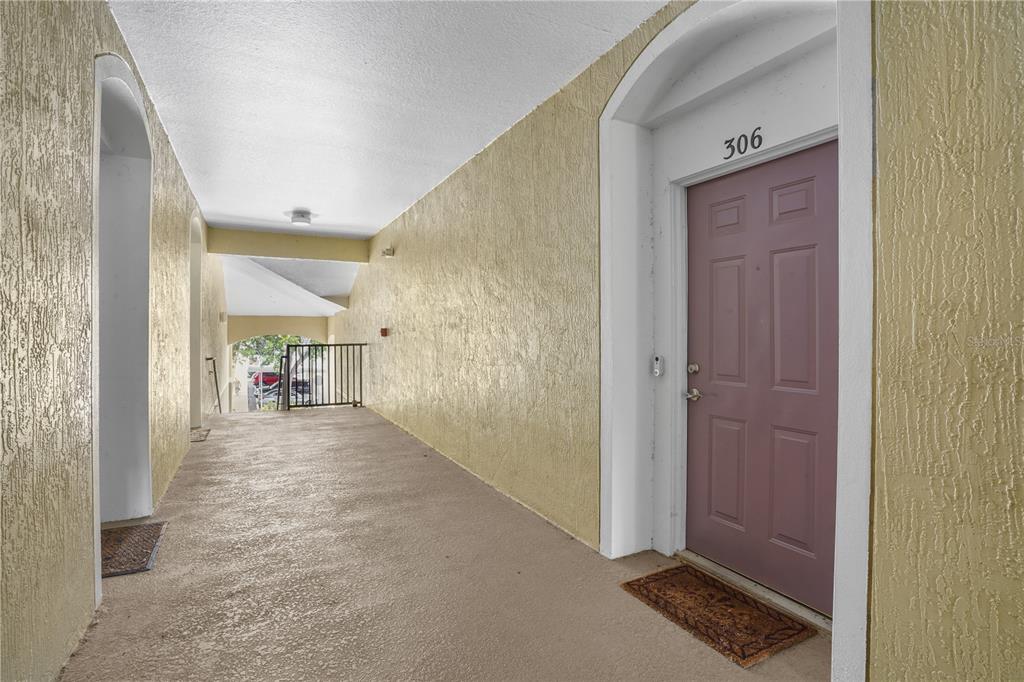 A covered outdoor walkway leads to a mauve-colored apartment door labeled 306 — 586 BRANTLEY TERRACE WAY UNIT 306, ALTAMONTE SPRINGS, FL