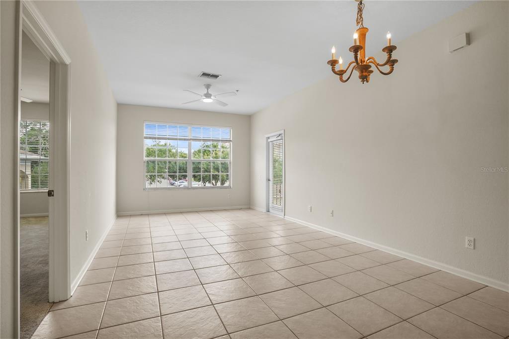 An empty dining room features beige tile flooring, a chandelier, and a large window — 586 BRANTLEY TERRACE WAY UNIT 306, ALTAMONTE SPRINGS, FL