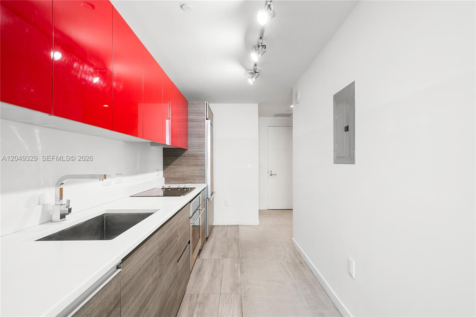 A modern kitchen features red upper cabinets, wood-grain lower cabinets, and white countertops — 1100 S Miami Ave # 2306, Miami FL 33130, MIAMI, FL