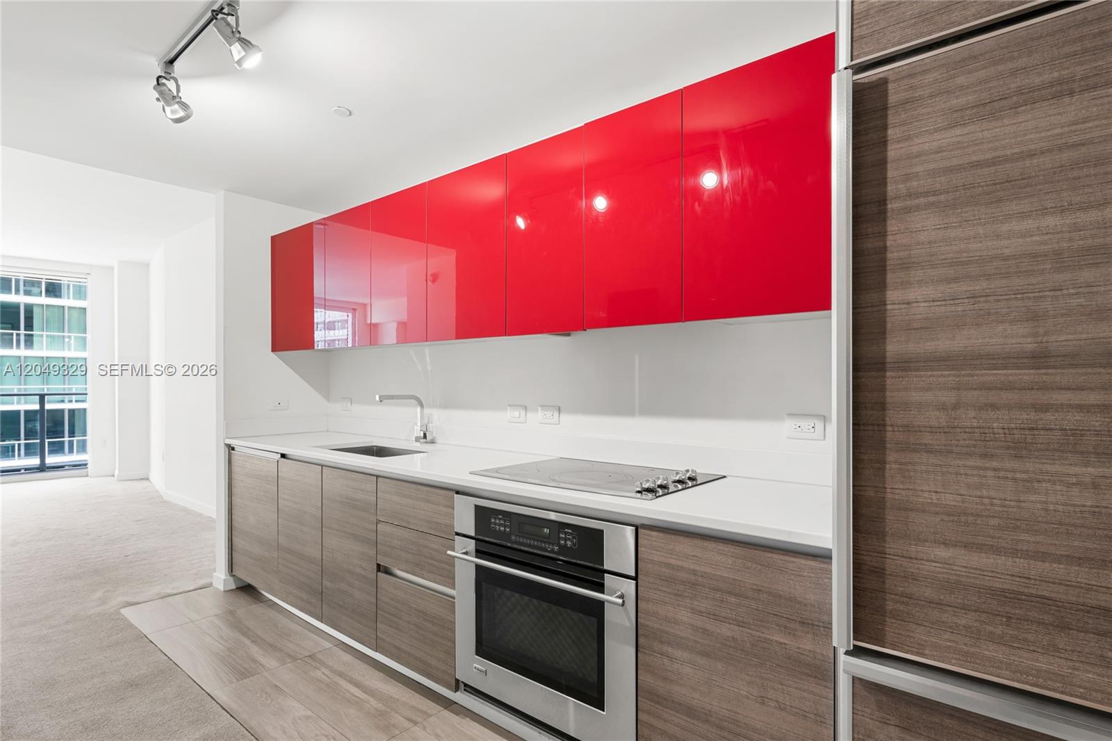 A modern kitchen features red upper cabinets, wood-grain lower cabinets, and a stainless steel oven — 1100 S Miami Ave # 2306, Miami FL 33130, MIAMI, FL