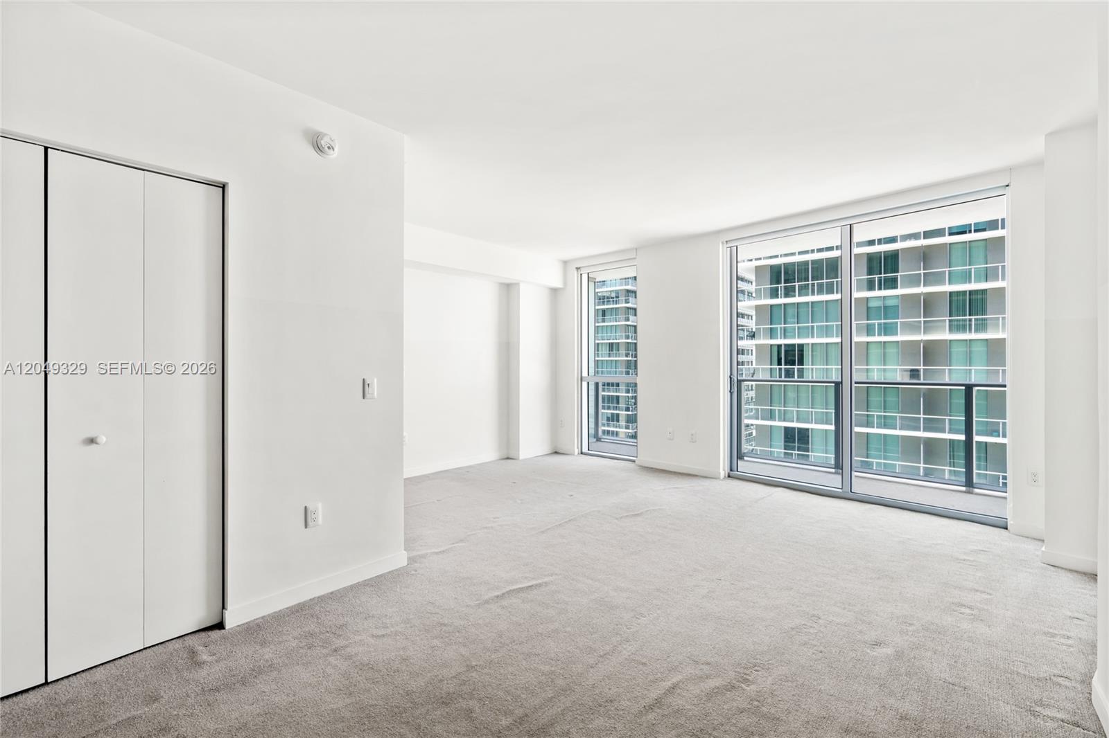 An empty room with white walls, gray carpeting, a closet, and floor-to-ceiling windows — 1100 S Miami Ave # 2306, Miami FL 33130, MIAMI, FL