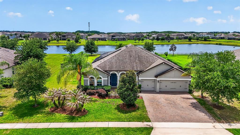 An aerial view shows a single-story suburban house with a paved driveway and a lake — 17614 SAILFIN DRIVE, ORLANDO, FL