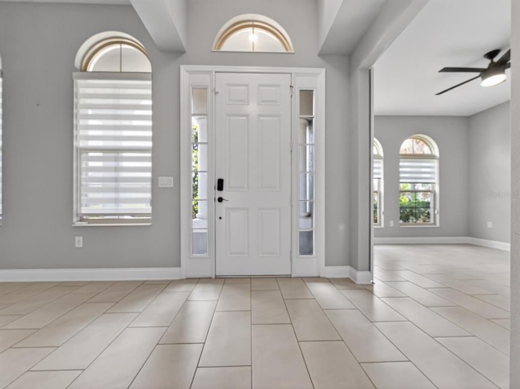 A bright entryway features a white front door with sidelights, arched windows, and tiled flooring — 17614 SAILFIN DRIVE, ORLANDO, FL
