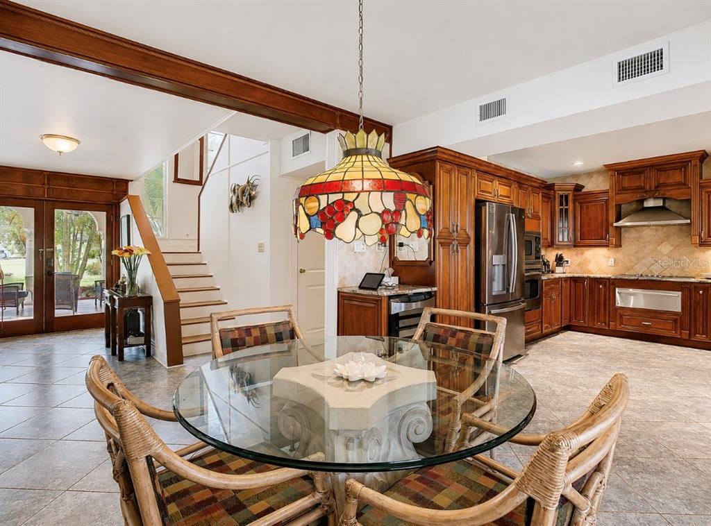 A dining area with a glass table, wicker chairs, and a stained-glass lamp near stairs — 4929 N RIVER SHORE DRIVE UNIT A, TAMPA, FL