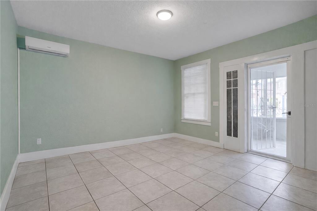 An empty room with light green walls, tile flooring, a mini-split unit, and glass doors — 316 W COLUMBUS DRIVE, TAMPA, FL