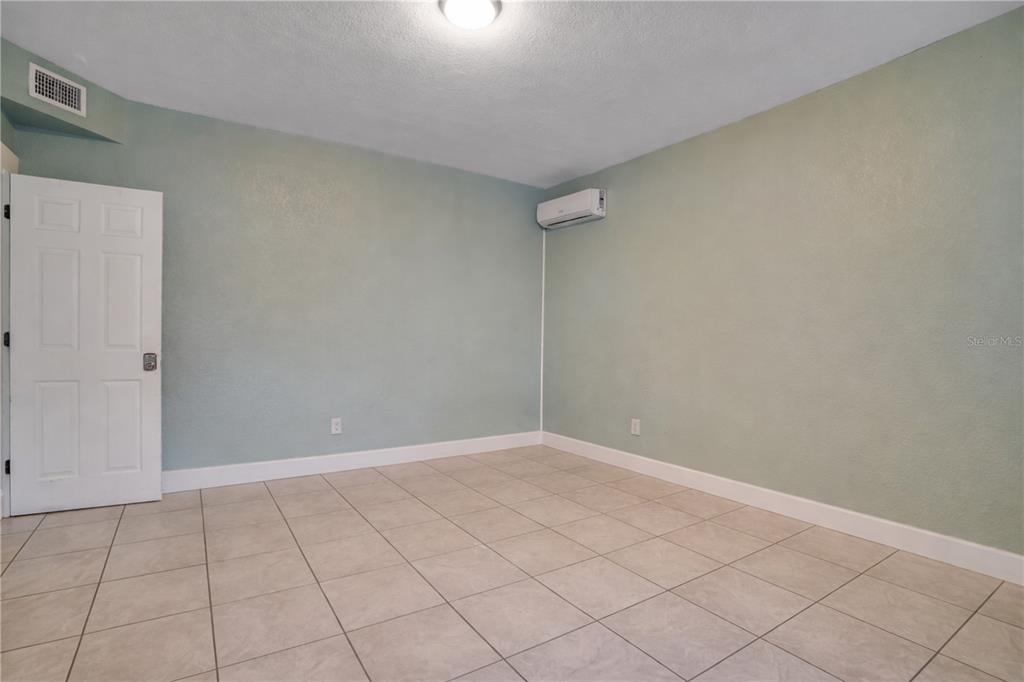 An empty room features light green walls, a tiled floor, and a wall-mounted air conditioner — 316 W COLUMBUS DRIVE, TAMPA, FL